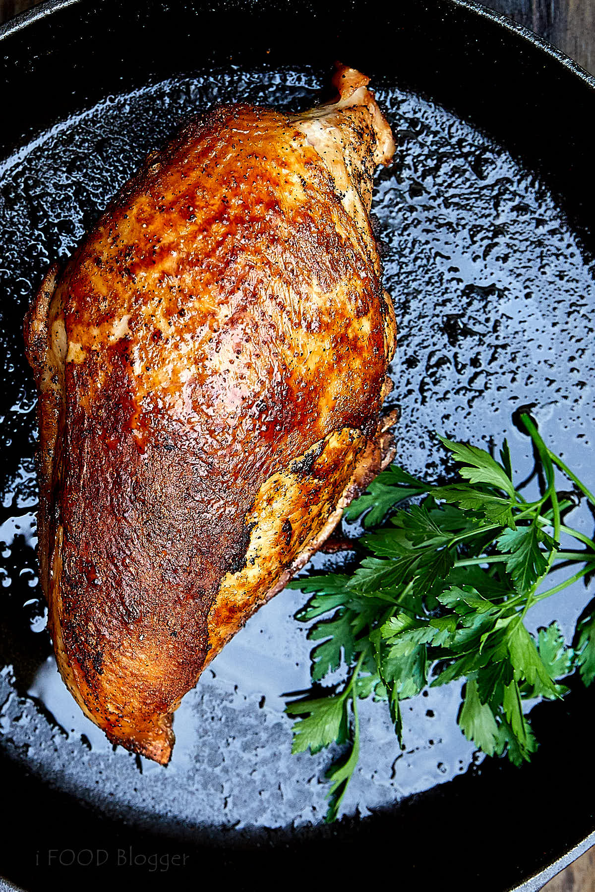 Close up of a golden-brown, crispy bone in turkey breast on a cast iron pan.