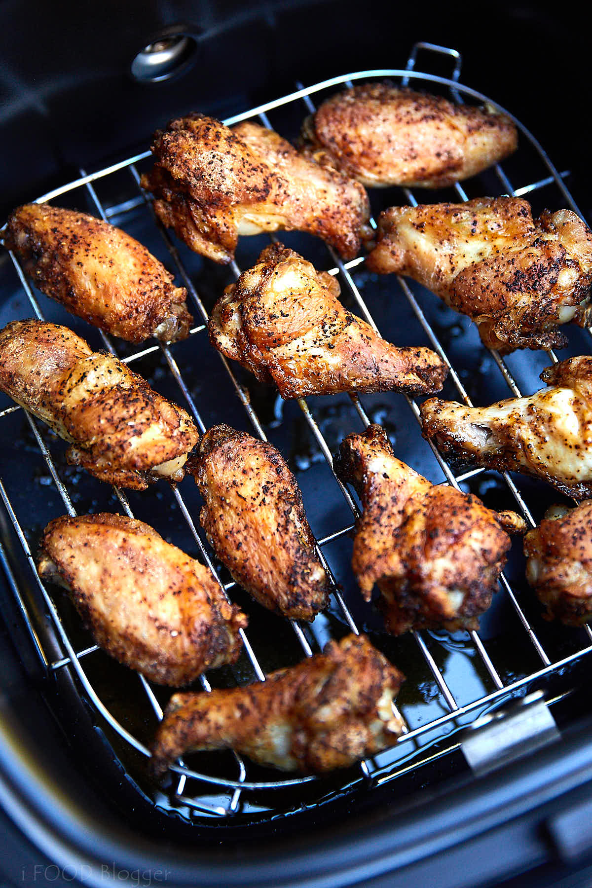 Golden-brown chicken wings on a rack of an air fryer.