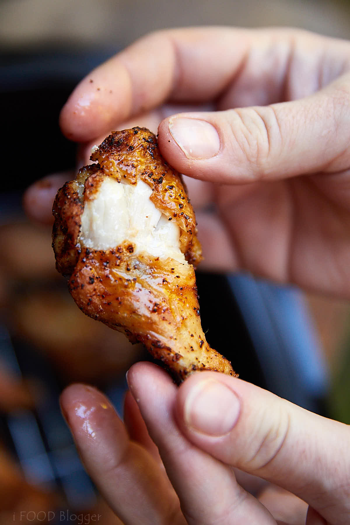 Close up of an air fried chicken wing, split open, showing juicy and moist meat under crispy skin.