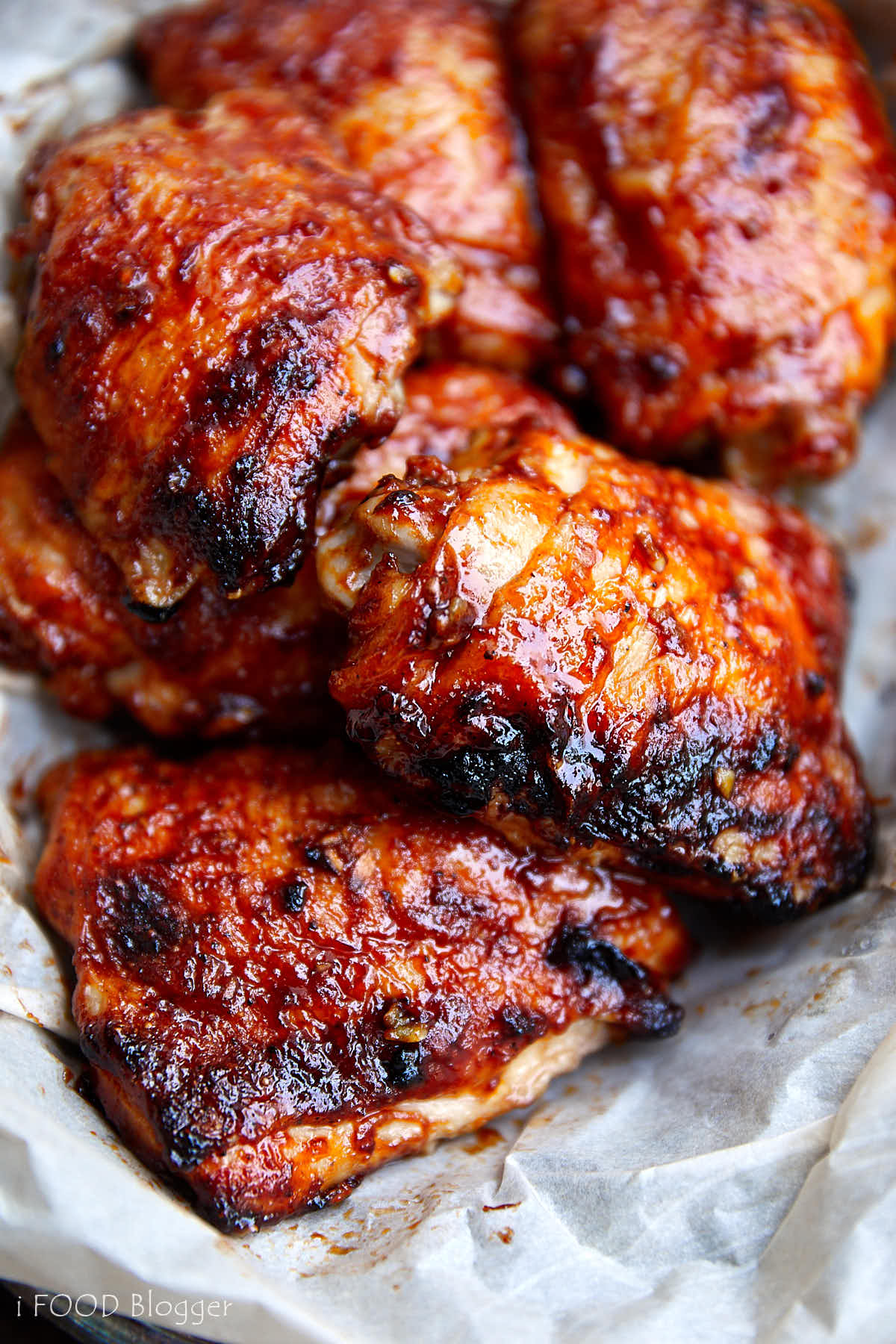 Baked BBQ chicken thighs, beautifully crisped up, saucy, in a serving basket lined with wax paper.