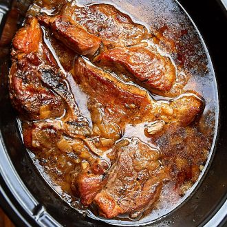 Country style pork ribs inside a Crock Pot filled with juices.