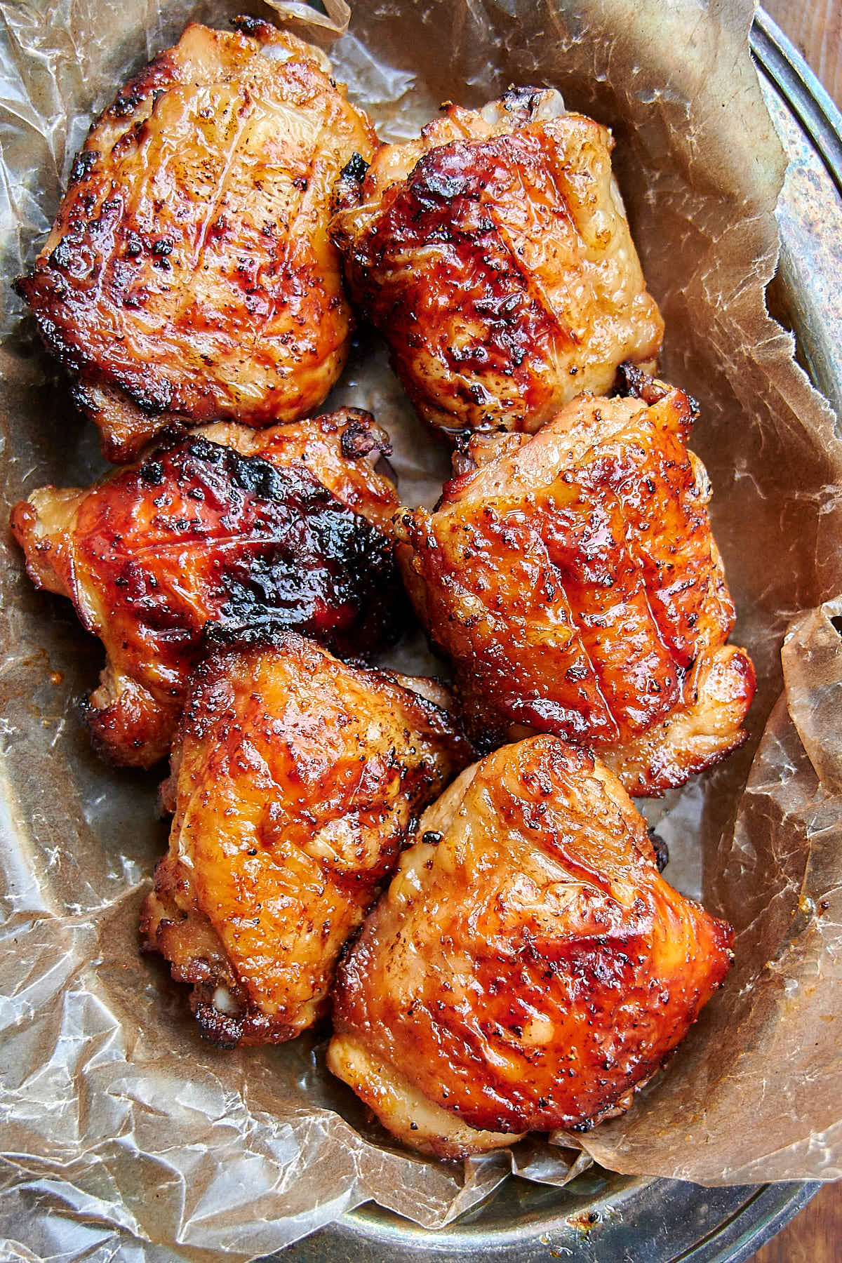 Golden-brown air fried chicken thighs in a serving basket lined with brown wax paper.