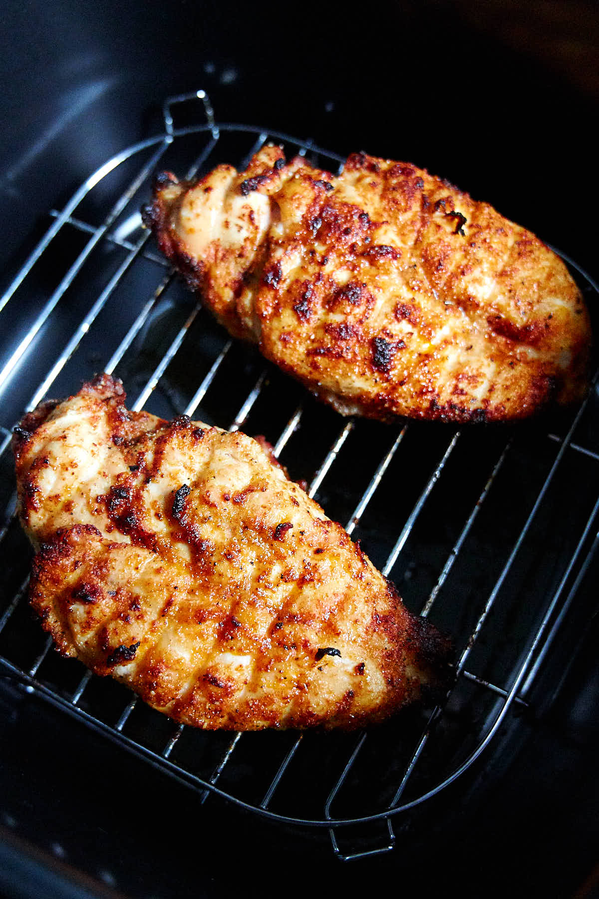 Close up of chicken breasts frying inside an air fryer.