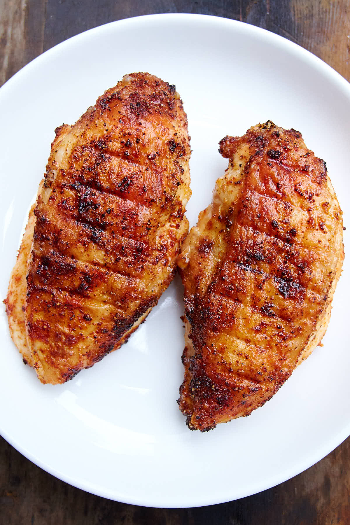 Deep golden-brown, crispy air fried chicken breasts on a white plate.