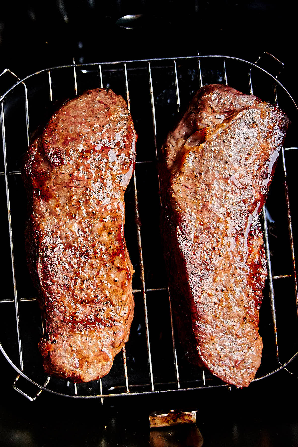 Two juicy steaks inside an air fryer.