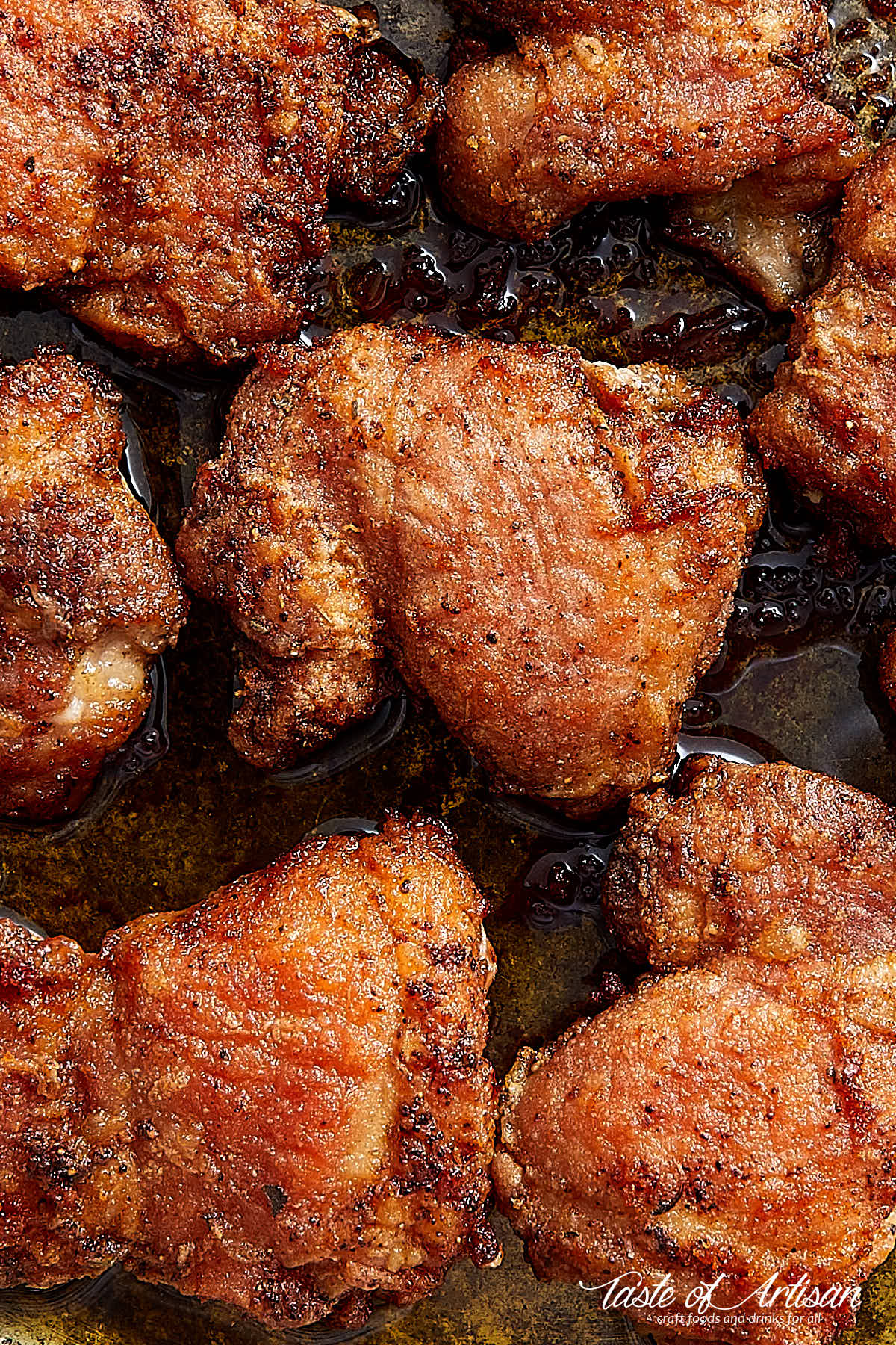 Close up of super crispu pan-fried boneless skinless chicken thighs on a skillet.