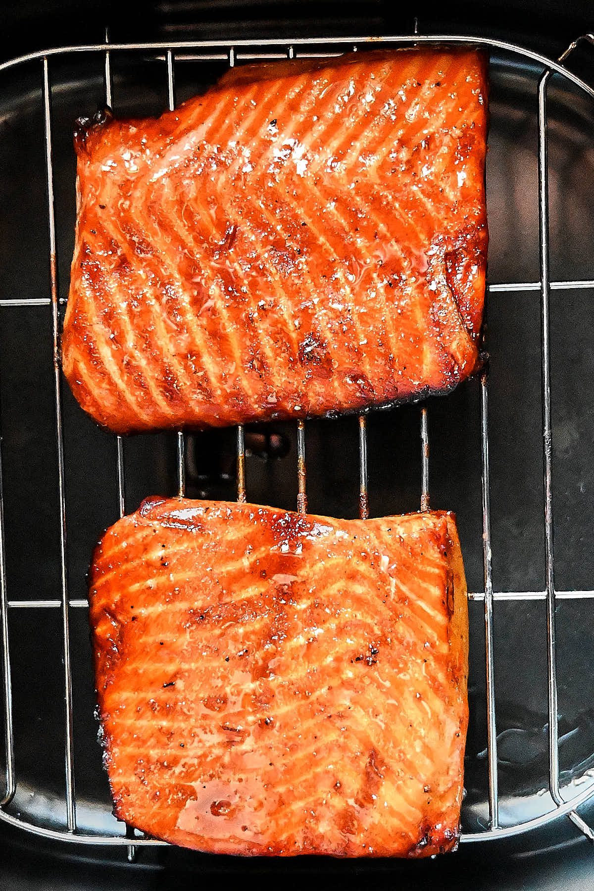 Air fried salmon pieces inside an air fryer on a rack.