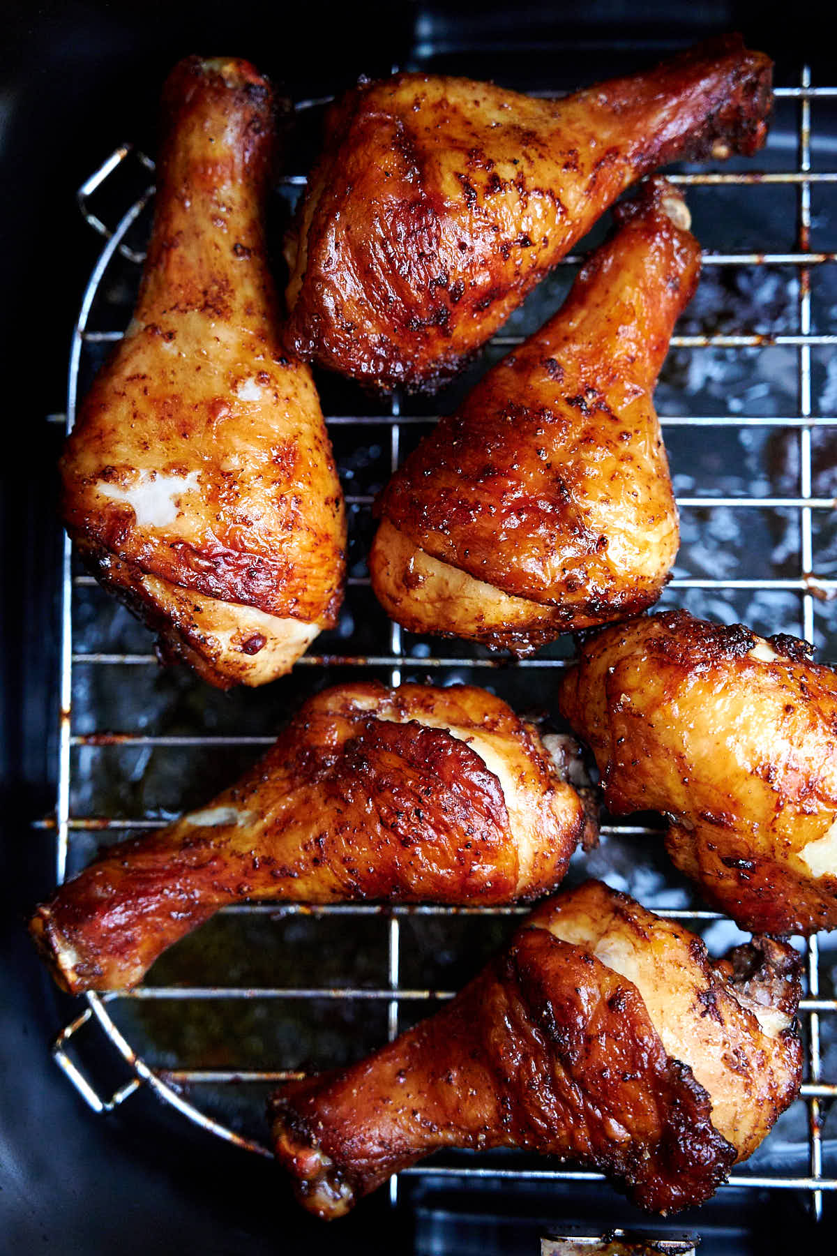 Air fryer chicken legs on a rack inside an air fryer, fully cooked.