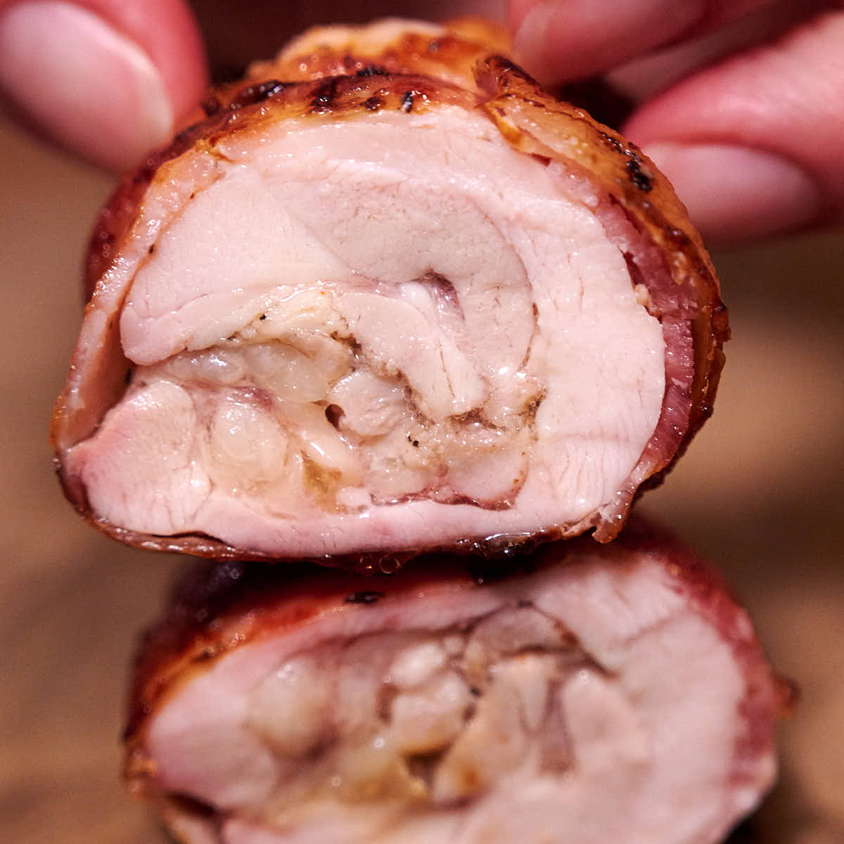 Sliced bacon wrapped chicken thigh, juices running off.