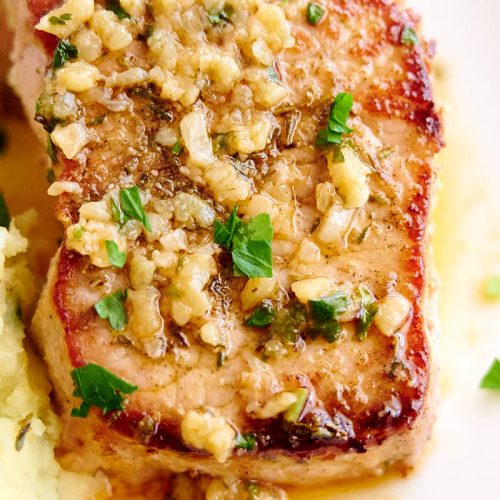 A delicious, juicy baked pork chop on a plate.