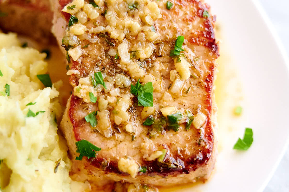 A delicious, juicy baked pork chop on a plate.
