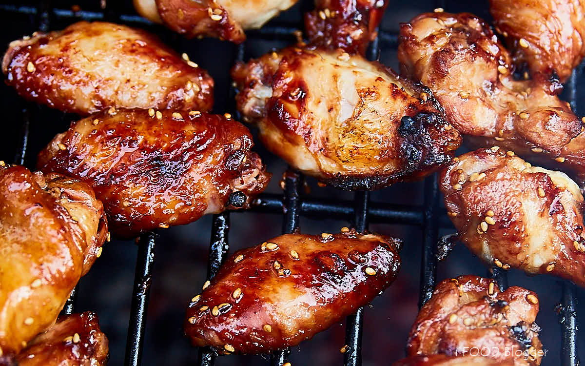 Asian inspired marinated chicken wings being grilled on a grill.
