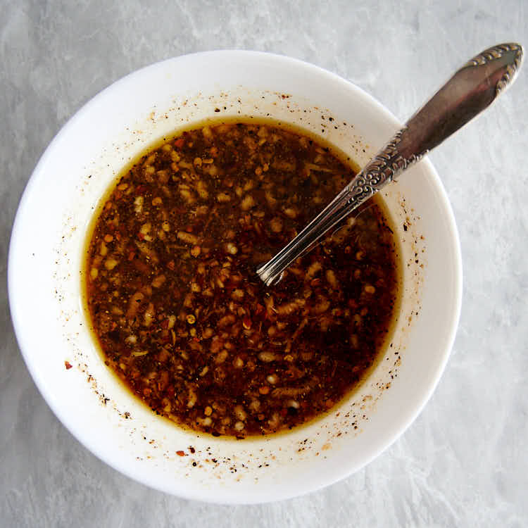 The best honey soy garlic chicken marinade in a white bowl with a spoon inside.