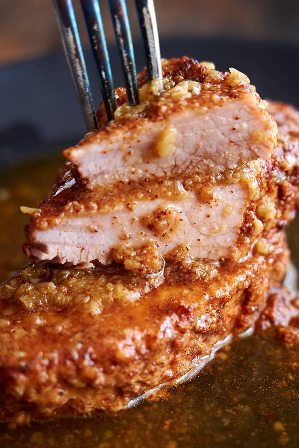 Boneless pork chops, cooked in Instant Pot, shown on a plate, cut in half, juicy, with amber honey garlic sauce on the plate.