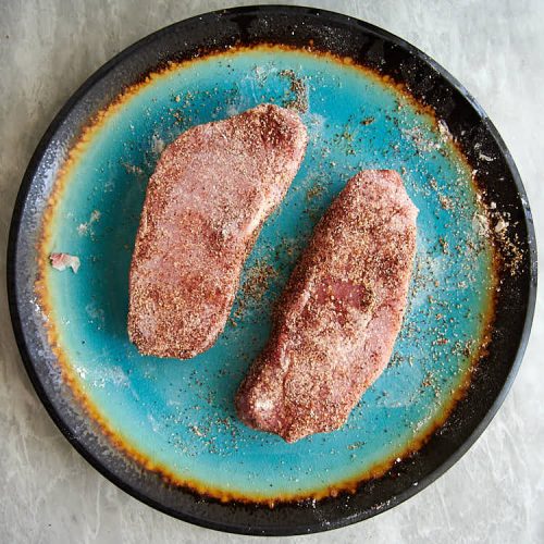 Seasoned pork chops on a plate.