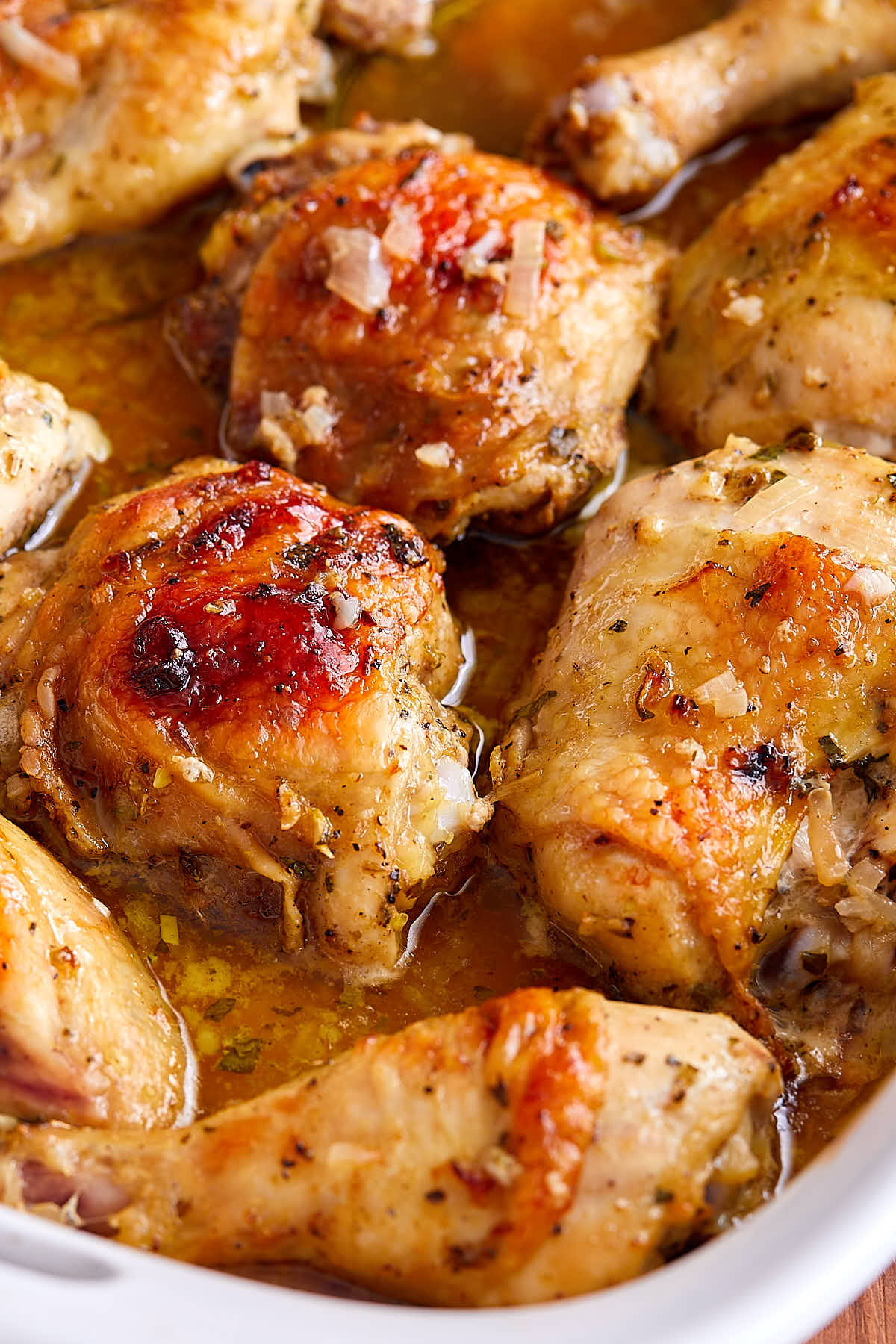 Partial view of roasted mojo chicken inside a white baking dish.