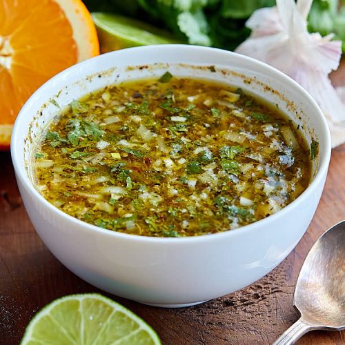 Mojo marinade in a white bowl on a wooden board.