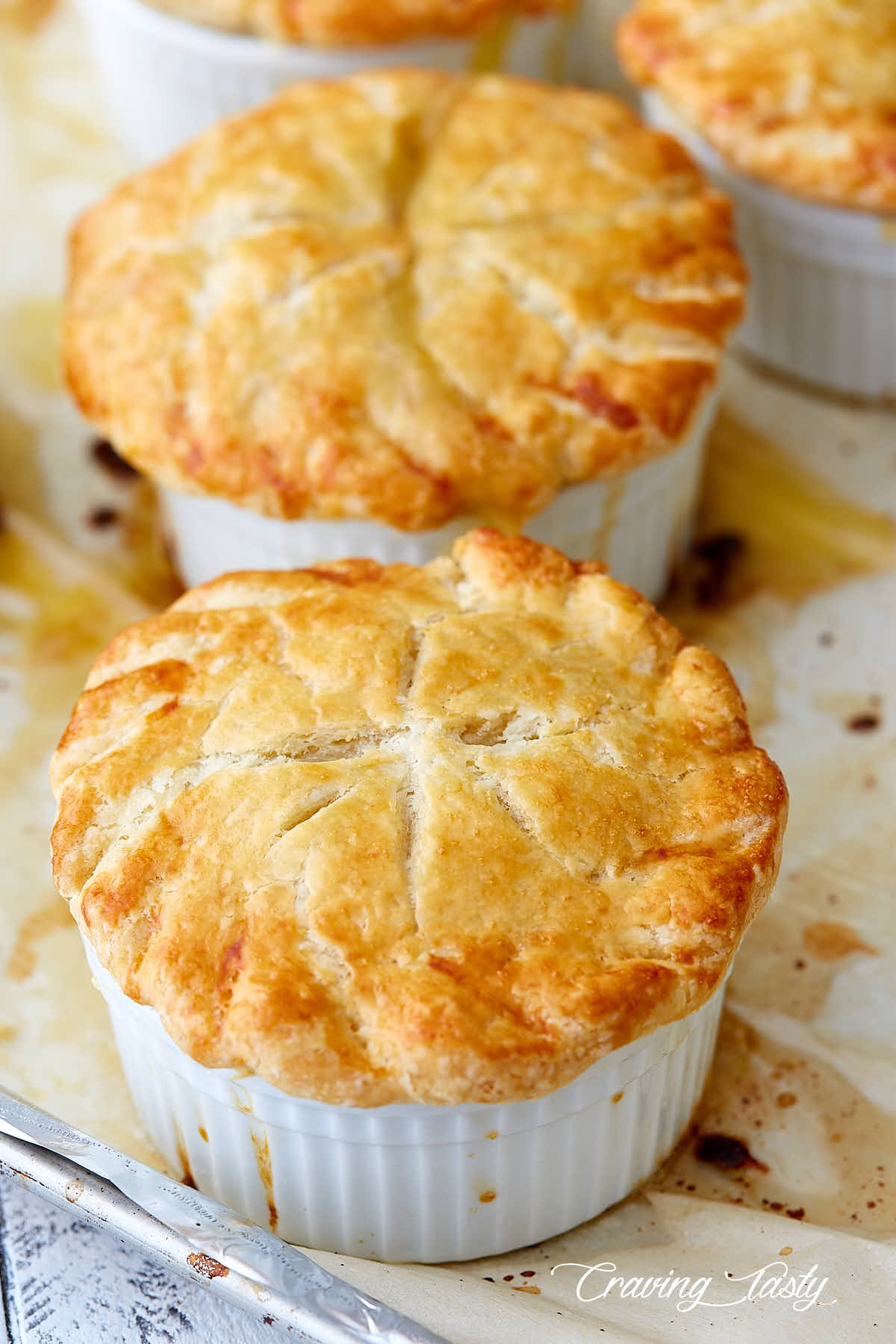 Two small chicken pot pies on a baking dish, with golden brown crusts.