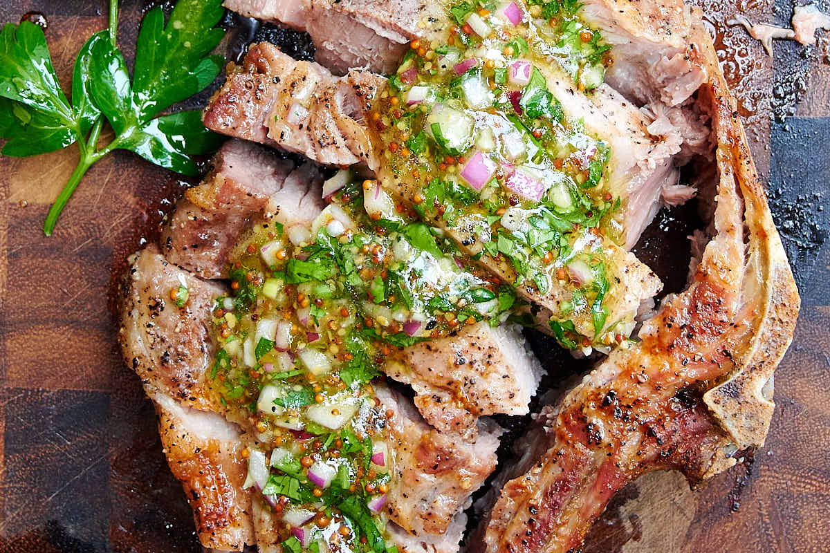 Close up of air fried pork chops topped with chimichurri sauce.