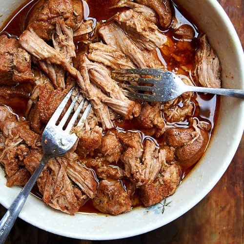 Close up of juicy pork being pulled with two forks.