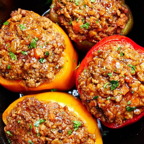 Four stuffed bell peppers inside a slow cooker.