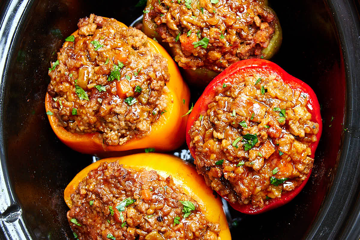 Four stuffed bell peppers inside a slow cooker.