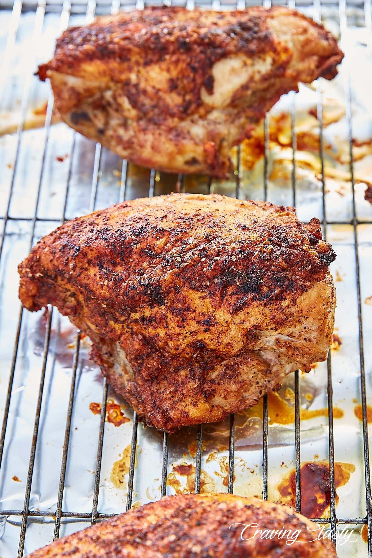 Three beautifully browned crispy baked chicken breasts on a cooling rack.