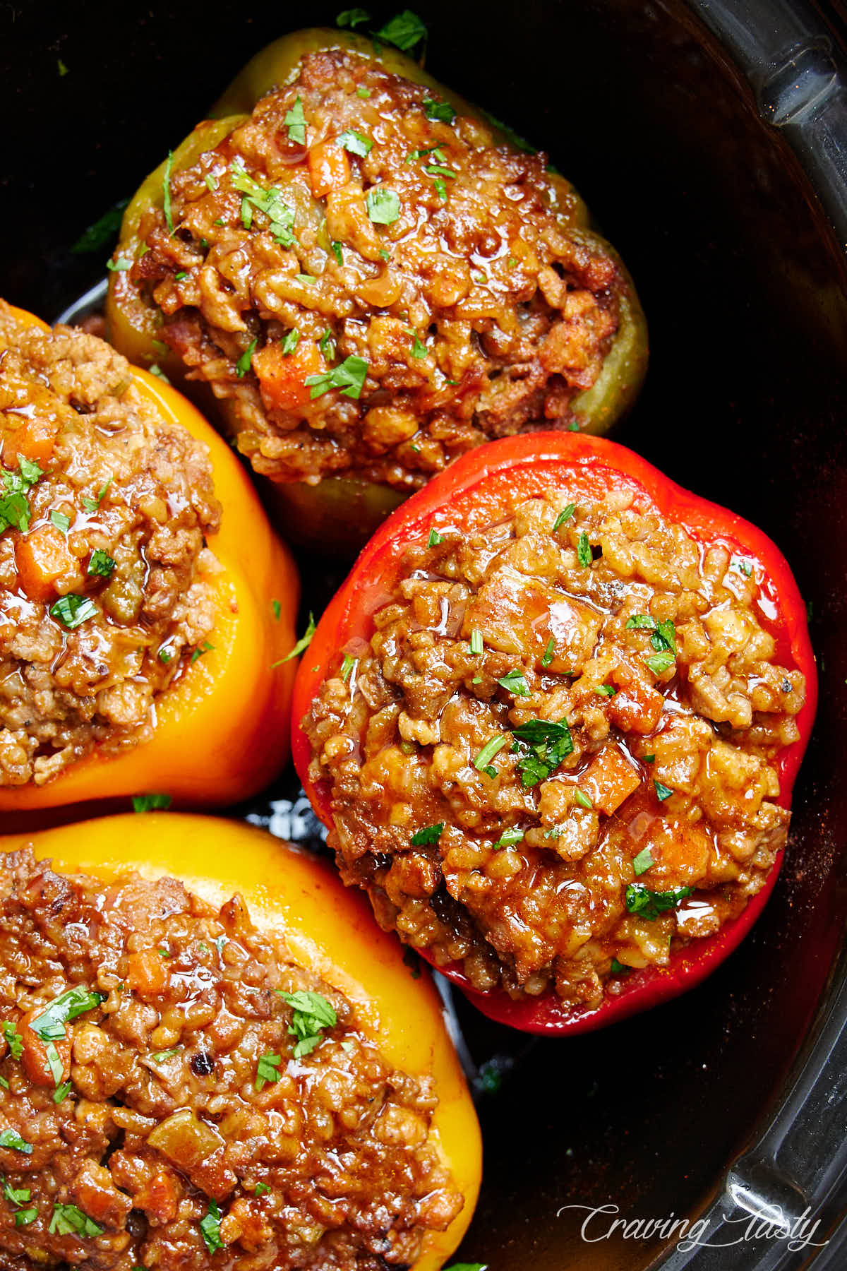 Four stuffed bell peppers inside a slow cooker.