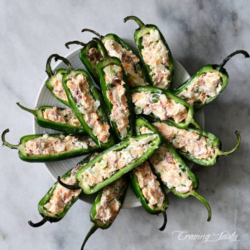 Raw stuffed jalapeno peppers on a plate.