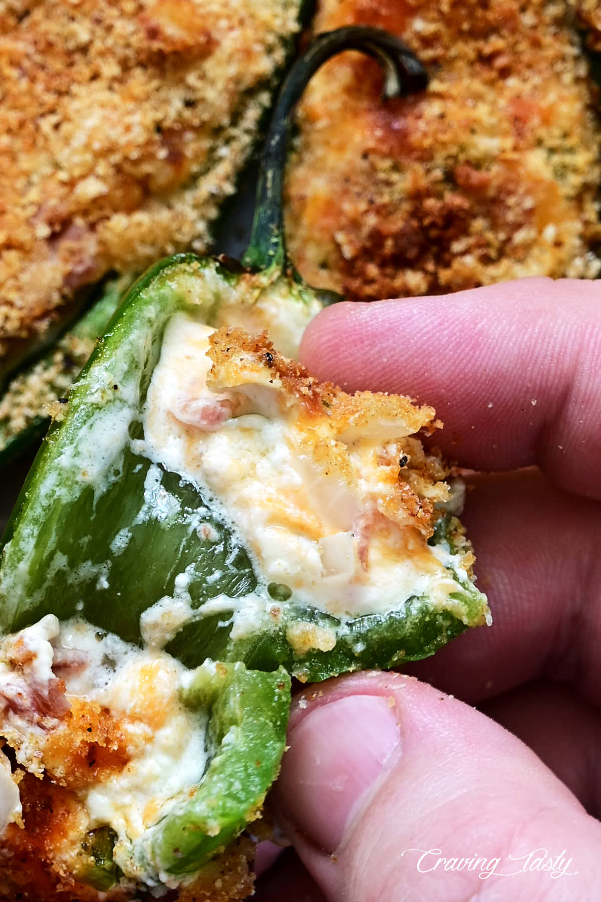 A close up of a jalapeno popper cut in half showing gooey cheese filling.