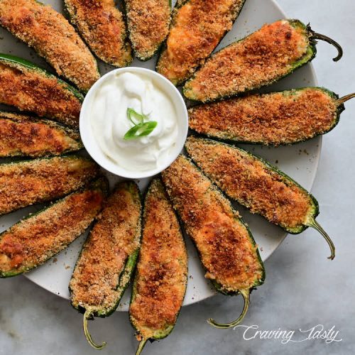 Baked jalapeno poppers on plate with a white dipping sauce.