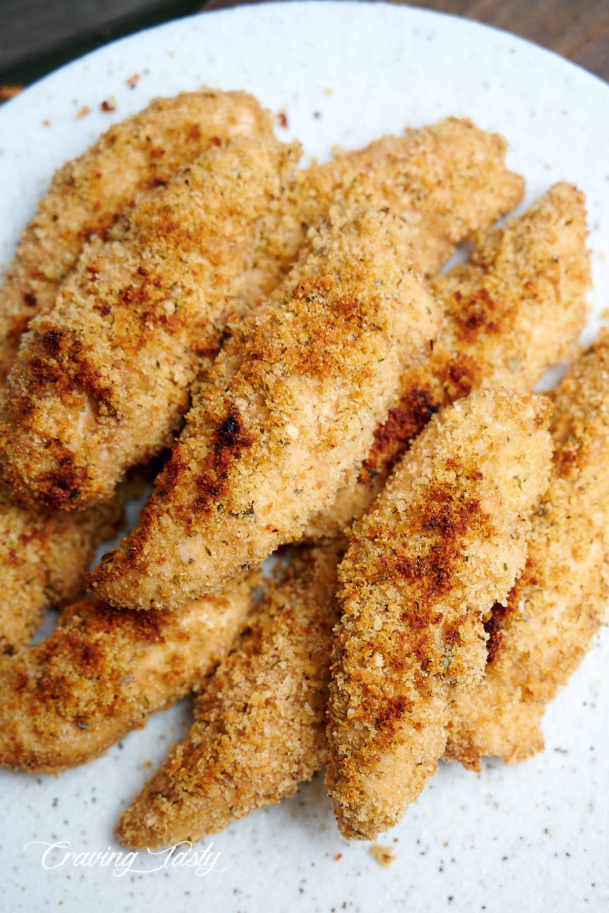 Golden brown, crispy chicken tenders on a speckled plate.