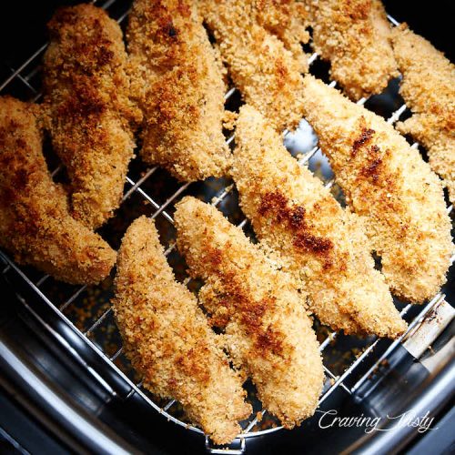 Golden brown chicken tenders inside air fryer.