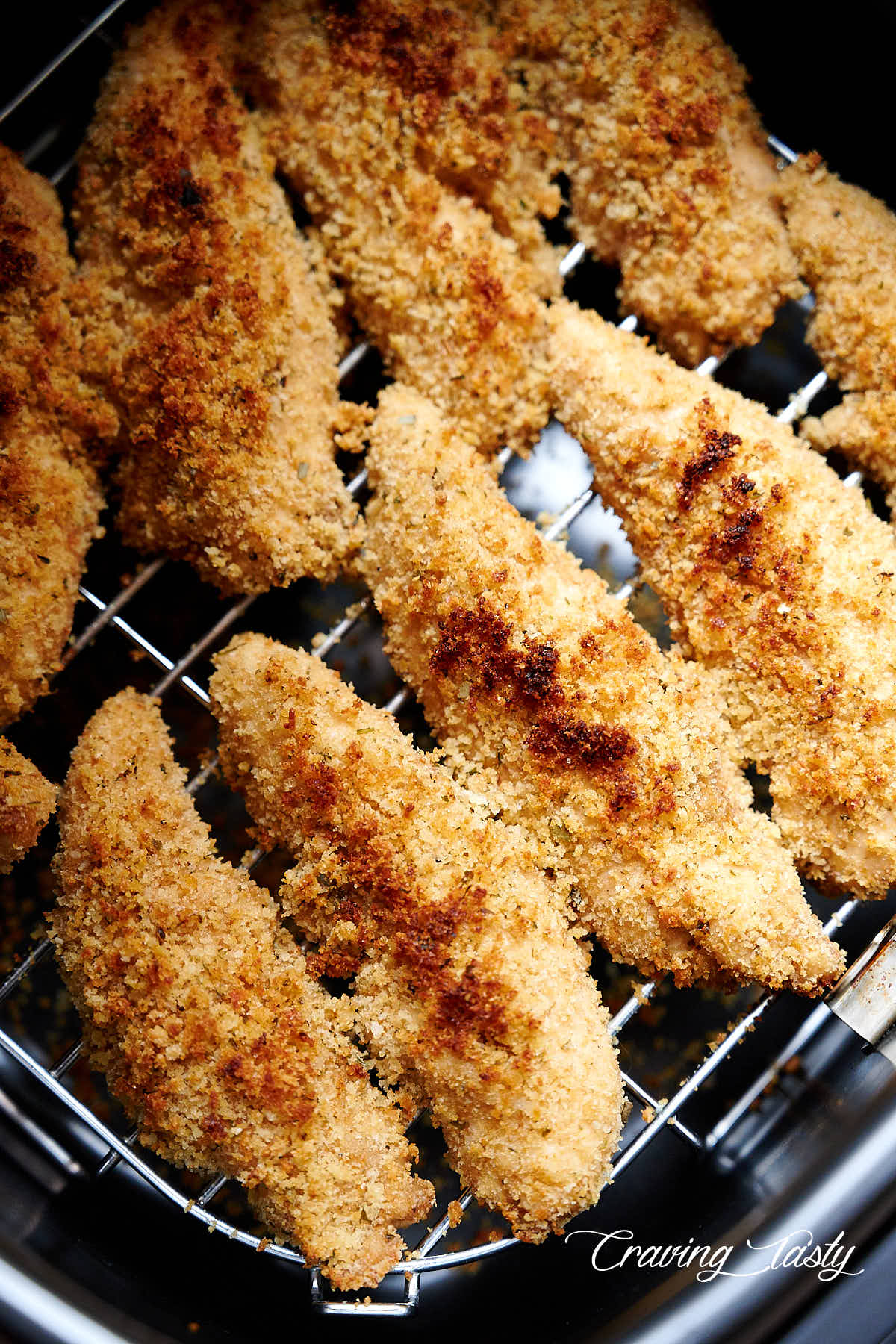 Golden brown chicken tenders inside air fryer.