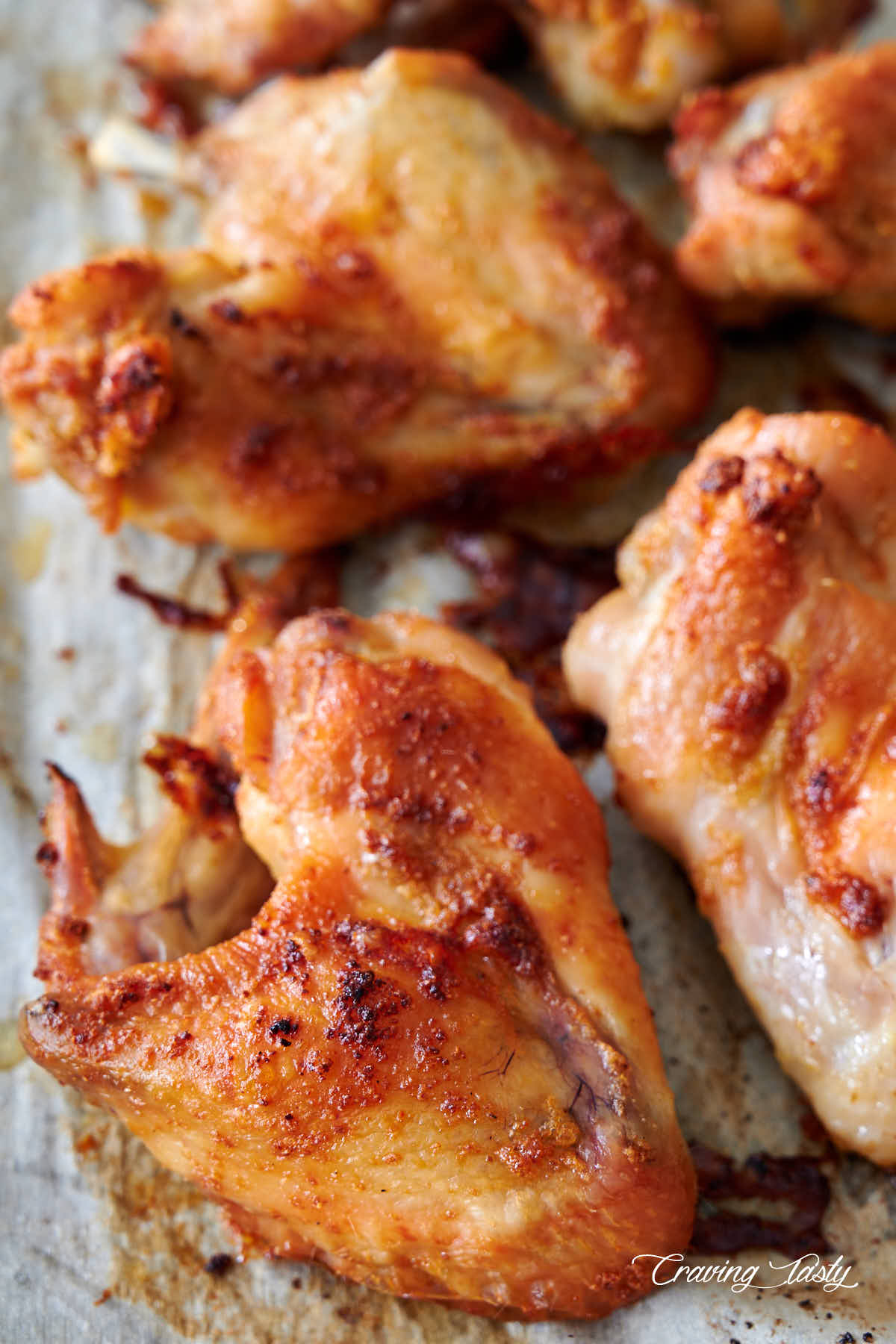 Close up of nicely browned chicken wings on parchment paper.