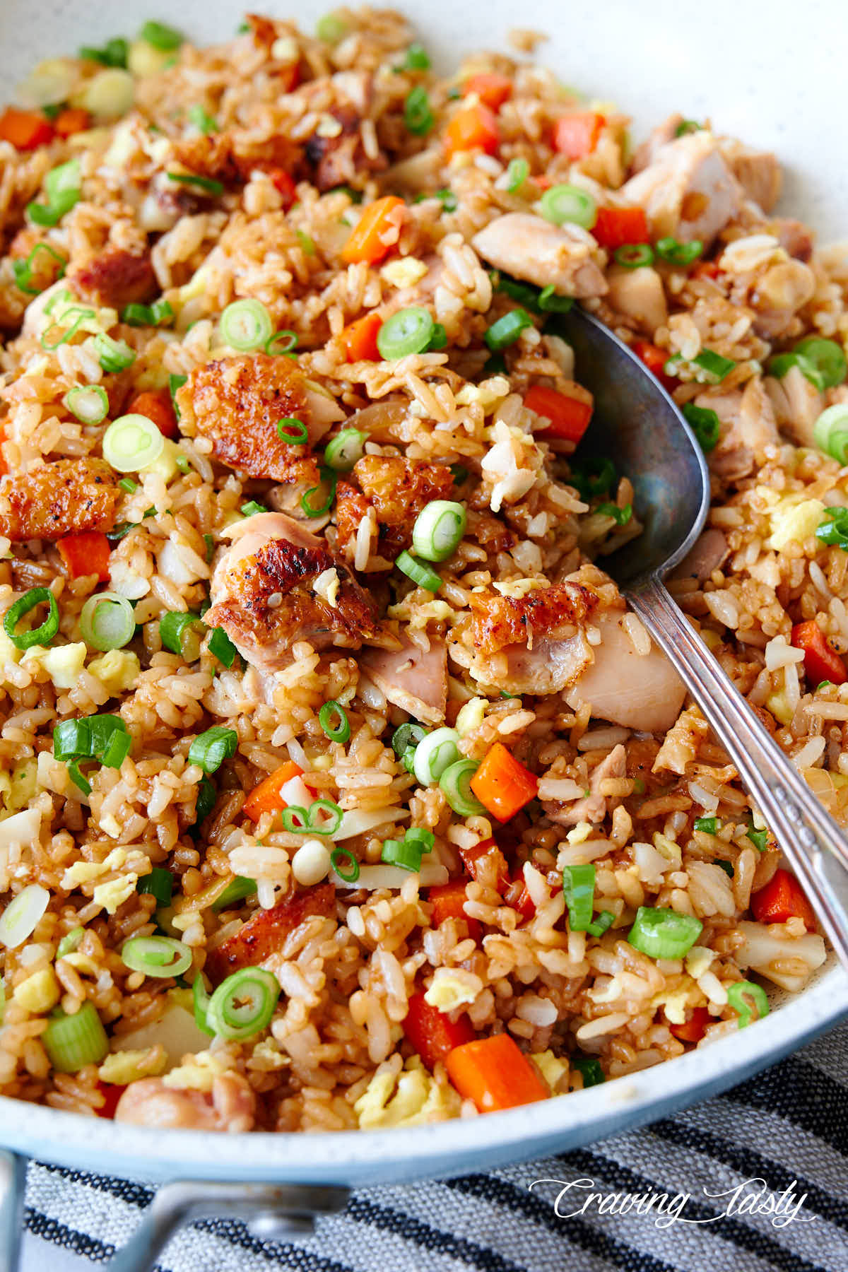 Chicken with fried rice on a white pan, on a kitchen table, view at an angle.