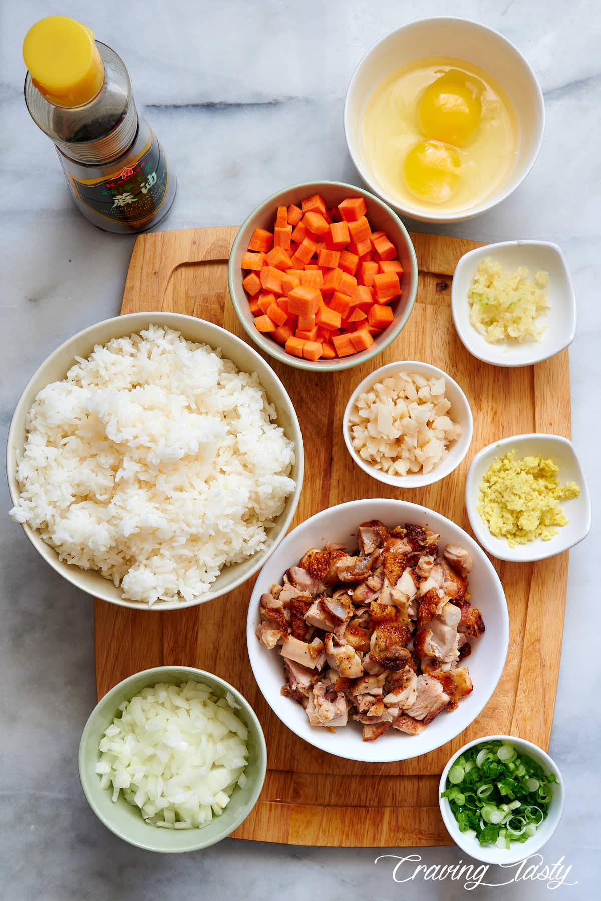 Ingredients for chicken fried rice in separate bowl on a table.