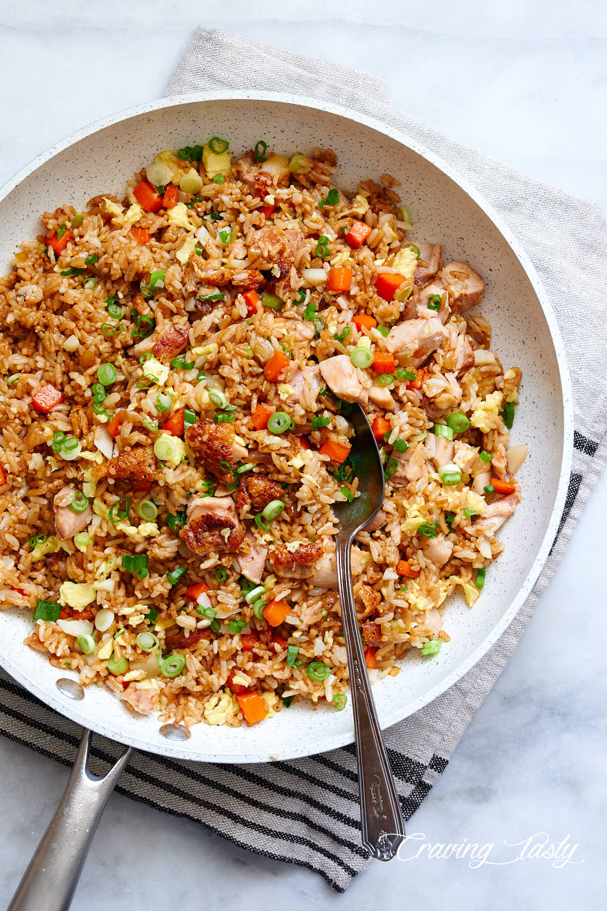 Chicken fried rice in a white pan on a marble table.