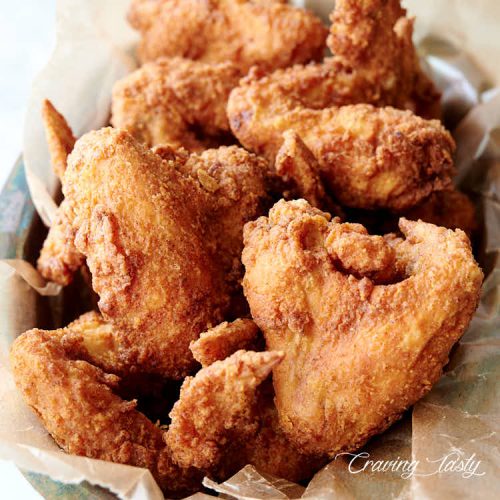 Crispy fried chicken wings in a basket.