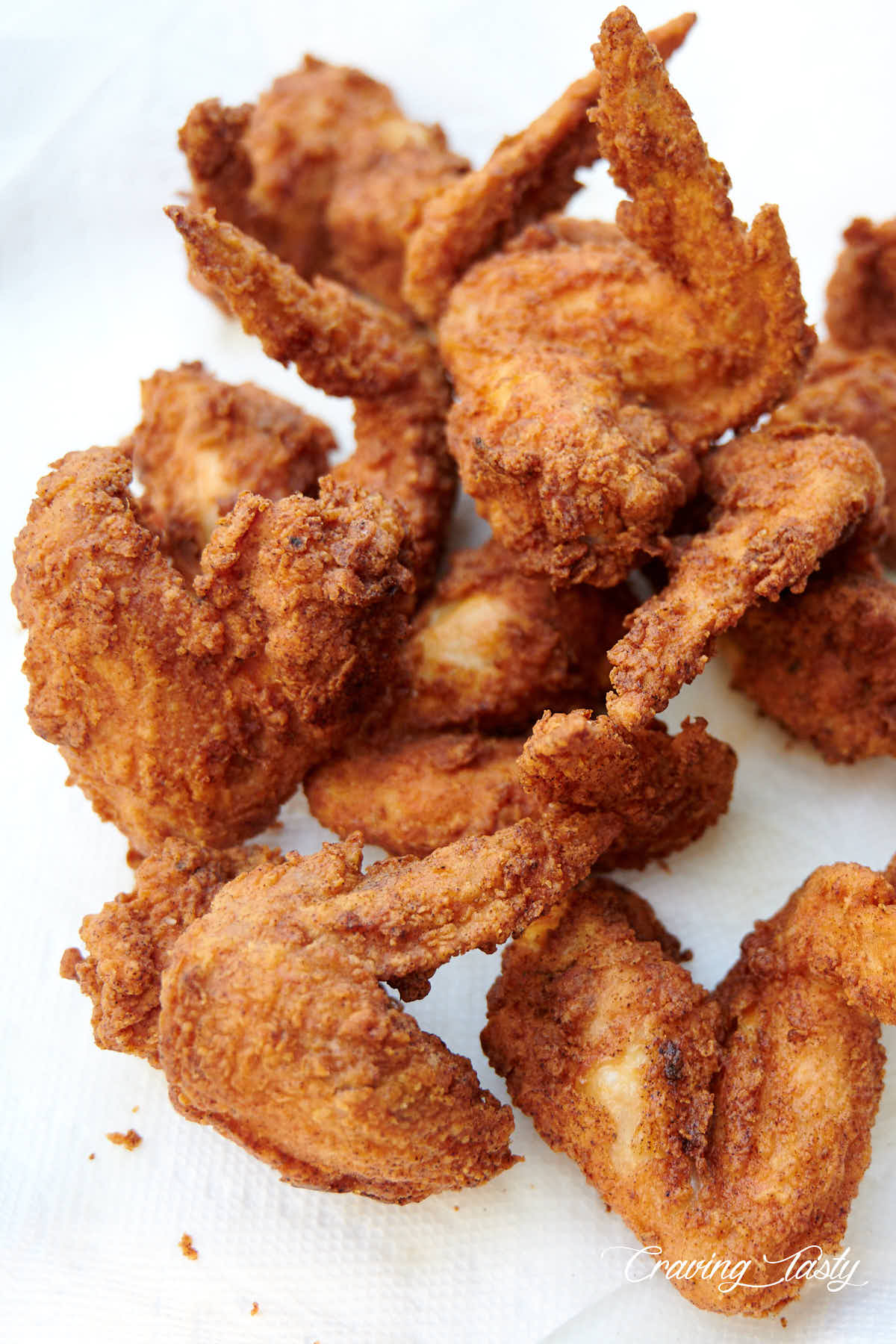 Crispy fried chicken wings on white paper towel.