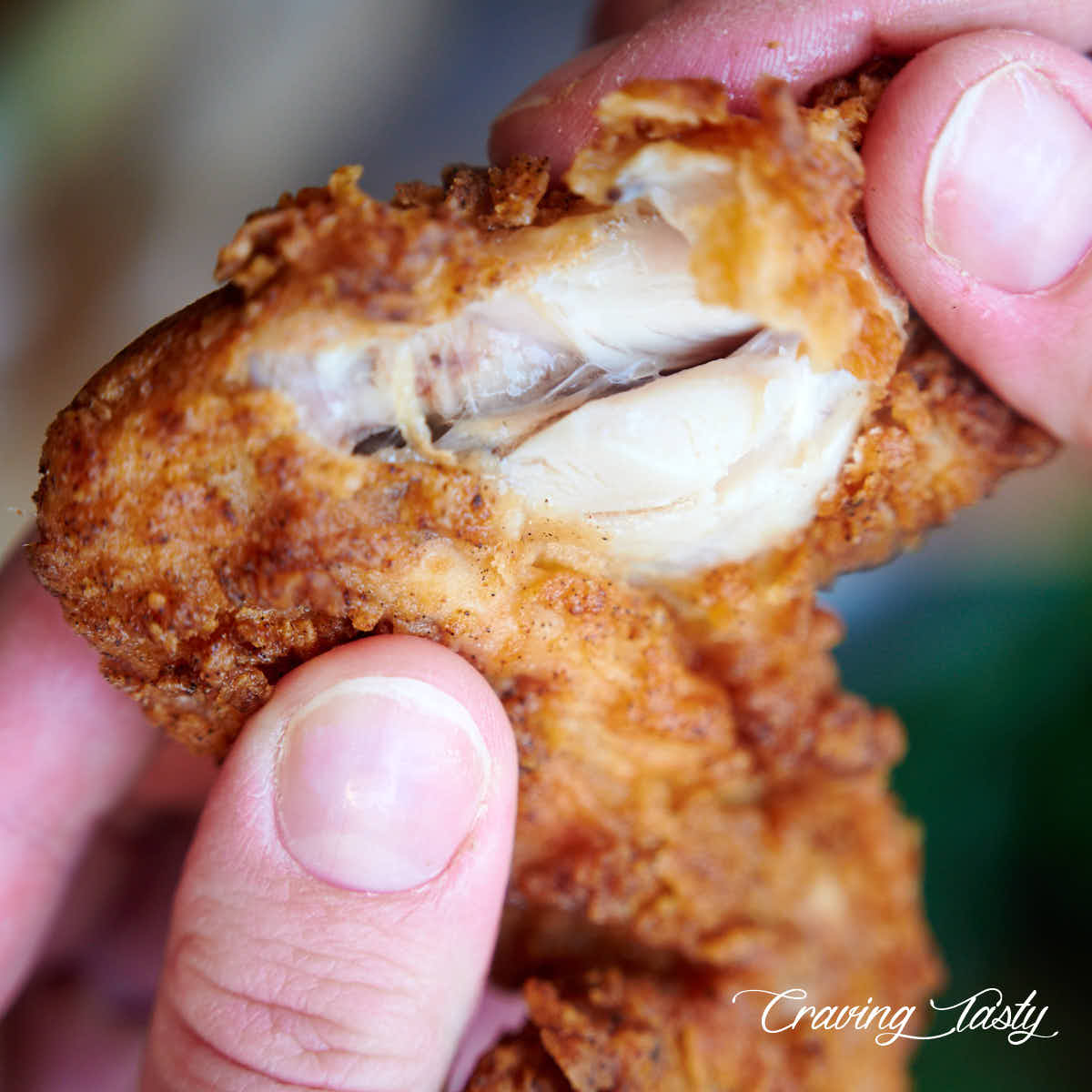 Golden brown fried chicken wings split open, showing moist, juicy meat.