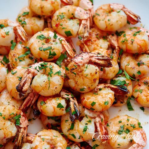 Close up of broiled shrimp on a white serving platter.