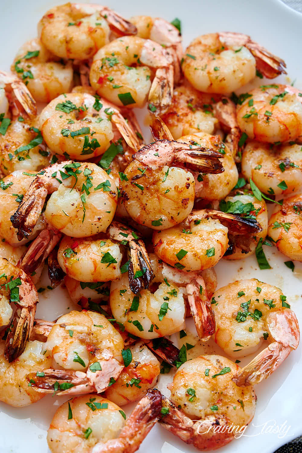 Close up of broiled shrimp on a white serving platter.