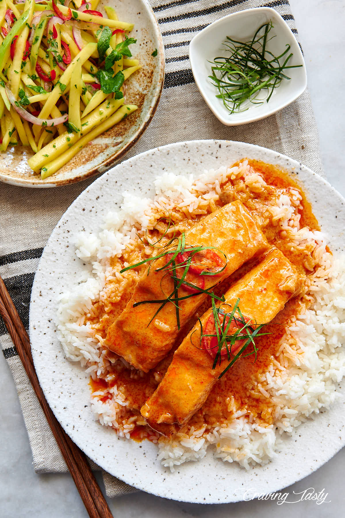 Salmon in red curry sauce with mango salad next to it.