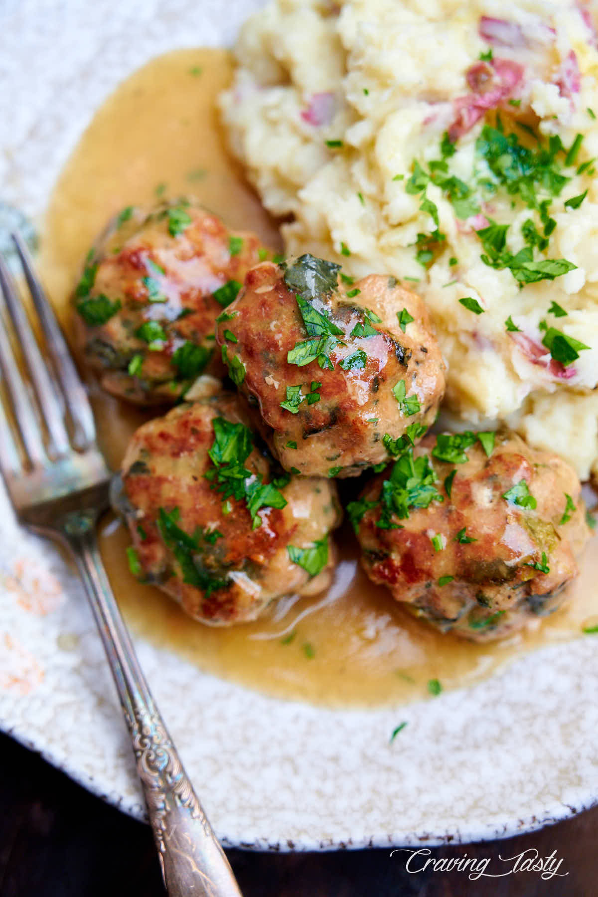 Turkey meatballs on a plate with mashed potatoes and gravy.