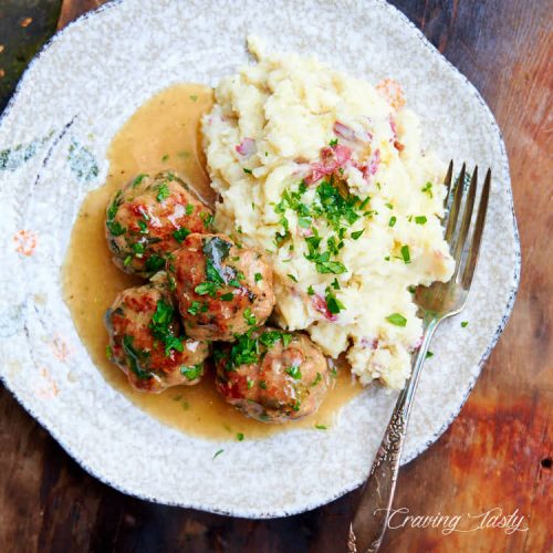 Top down view of turkey meatballs on a plate with mashed potatoes and gravy.