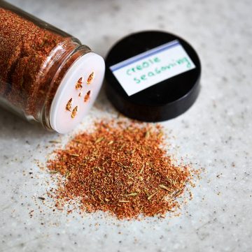 Creole seasoning on a table with the jar next to it.