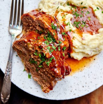 Meat loaf made in Instant Pot on a plate with mashed potatoes and gravy.