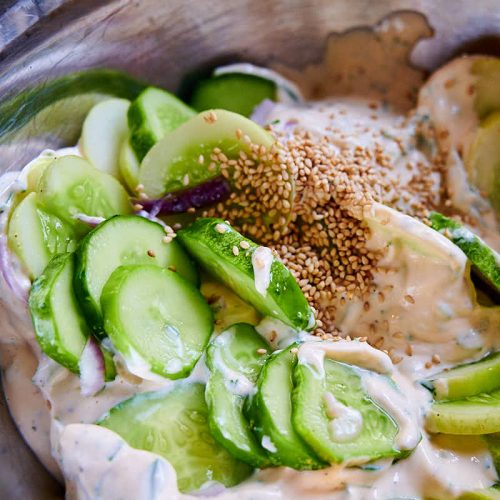 Mixing cucumbers with mayo and other ingredients.