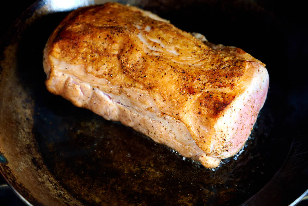 Golden brown seared pork loin roast on a pan.